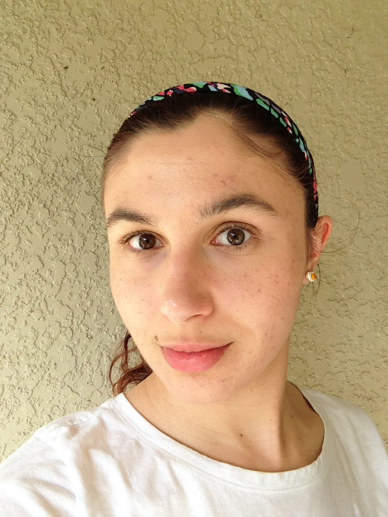 Ashlee Craft wearing a white t-shirt, cute kawaii egg earrings, & multicolored headband